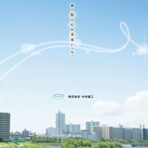株式会社中村建工 様 会社案内制作実績：ライトブルーとグリーンの背景にそびえ立つ未来的なオフィスビル