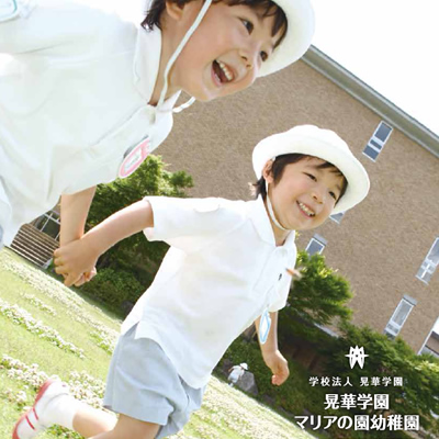 晃華学園マリアの園幼稚園 様 募集パンフレット制作実績：晃華学園マリアの園幼稚園の先生と園児たちが手をつないで笑顔で歩く様子